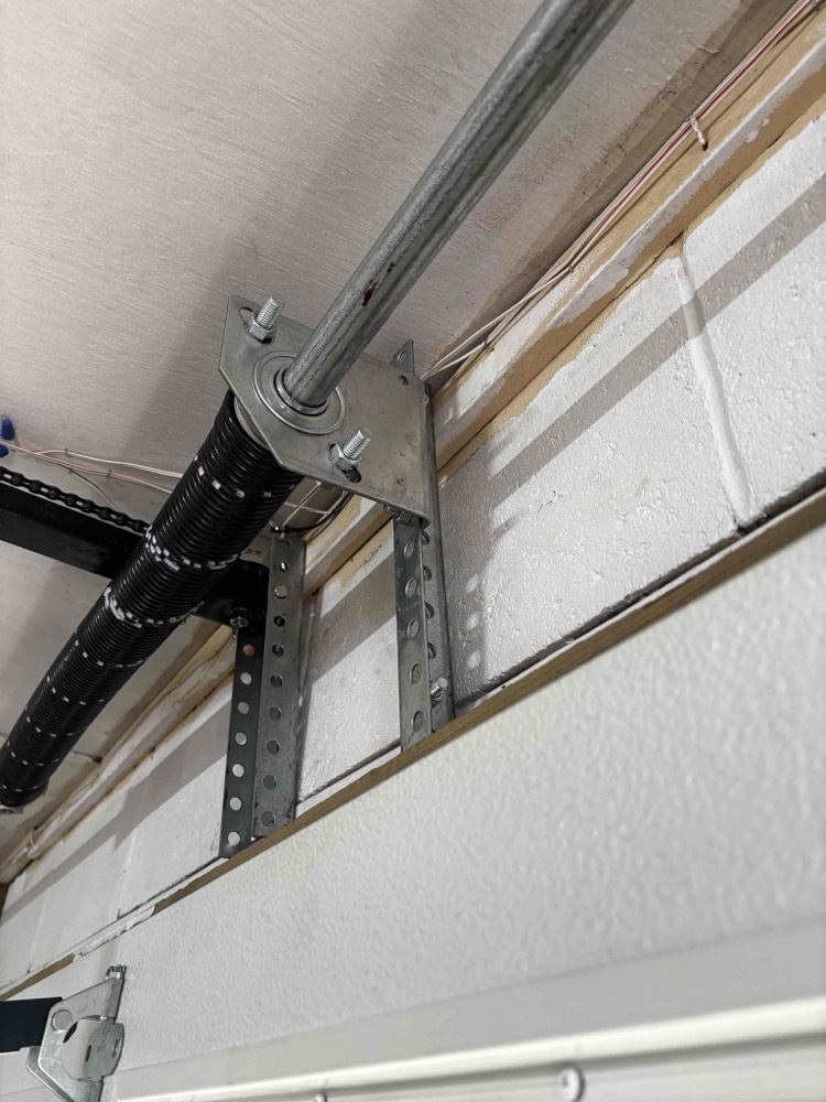 Torsion spring and pulley bracket mounted on garage door frame