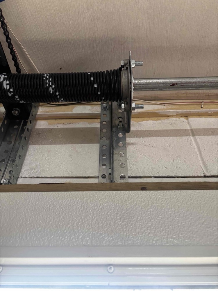 Torsion spring and mounting hardware on garage door frame