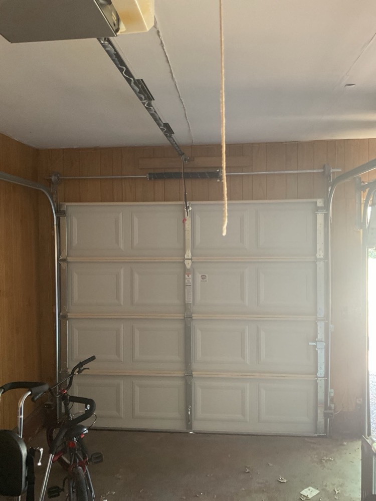 Two white paneled garage doors with tracks and opener system installed