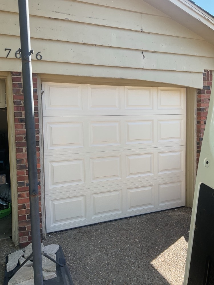 White paneled garage door installed on brick and vinyl house in Bethany