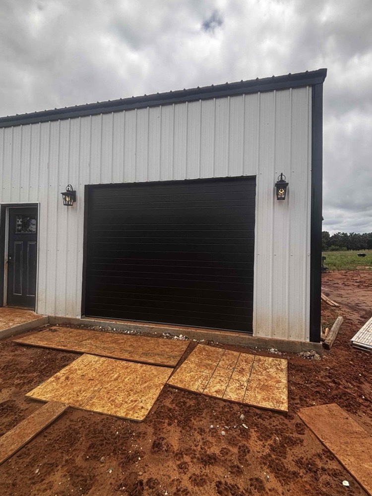 Newly installed black garage door on white metal building