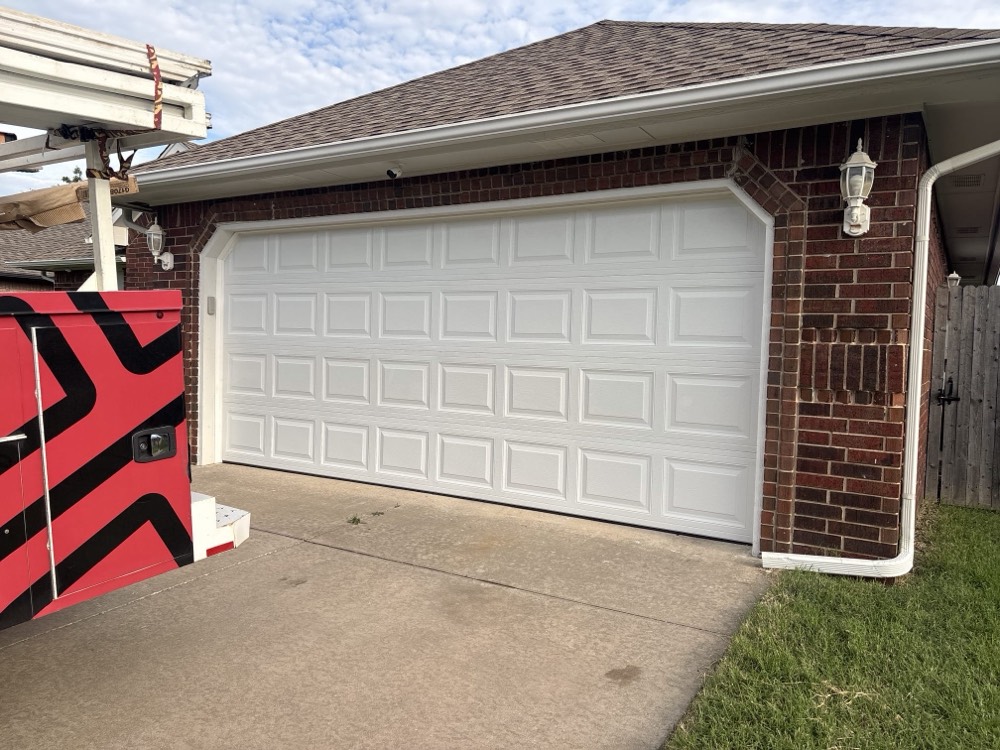 Newly installed white garage door on brick residential home