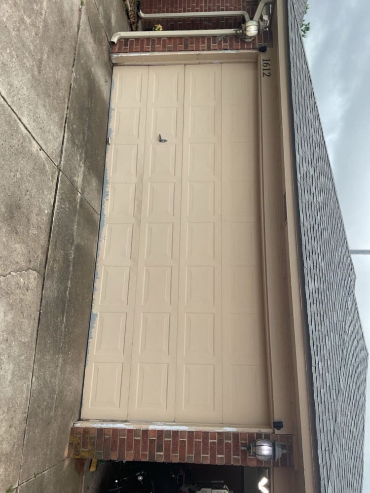 Newly installed cream garage door with clean appearance on brick exterior