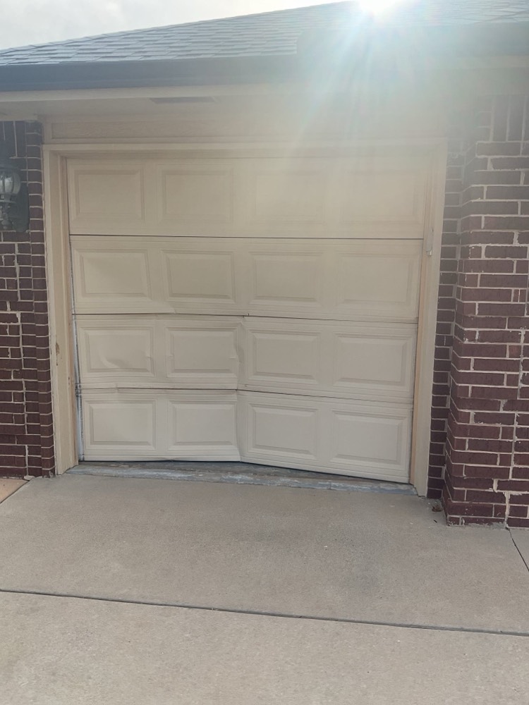 Newly installed white garage door on brick home with driveway.