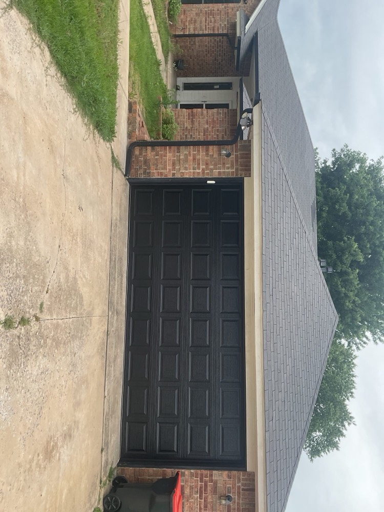 Black multi-panel garage door installed on brick home exterior