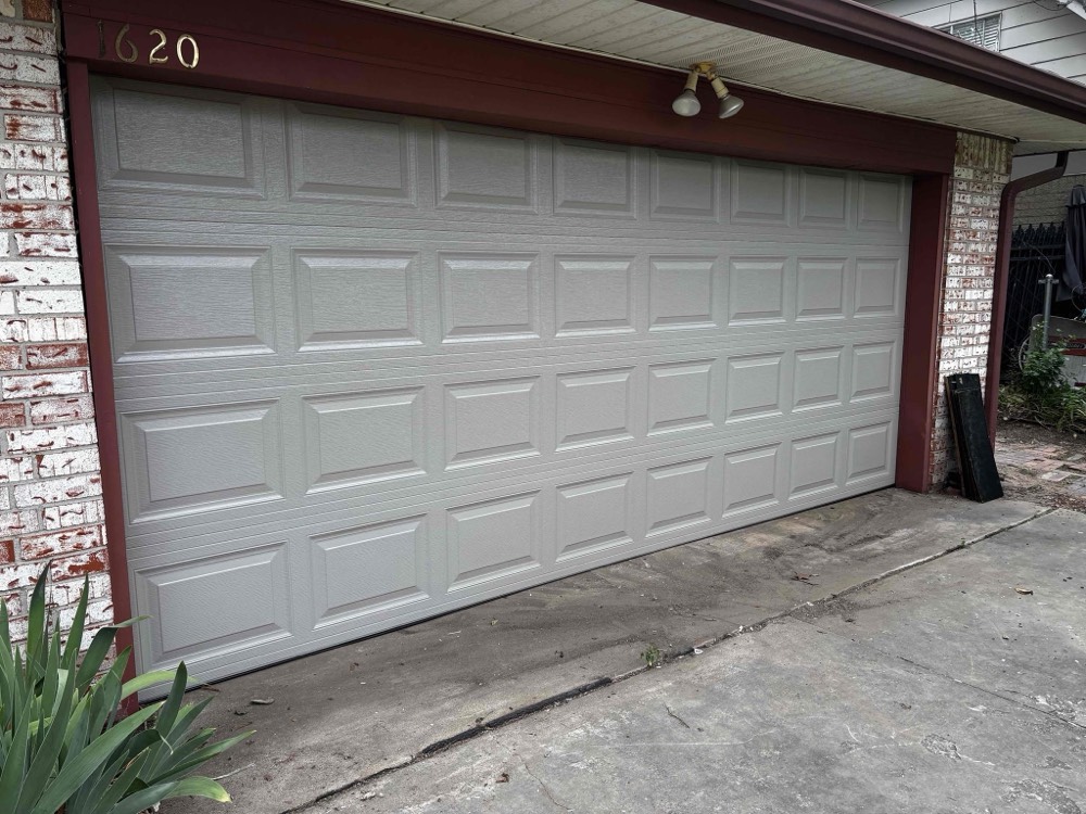 White multi-panel garage door installed on brick home with maroon trim