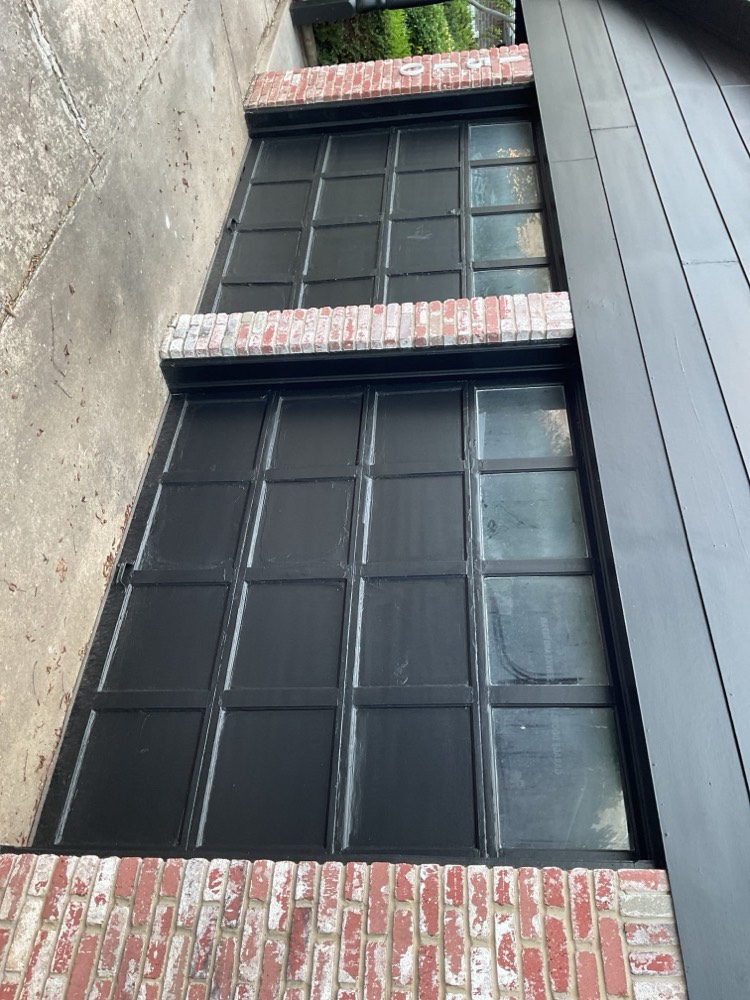 Two black multi-panel garage doors with glass window inserts