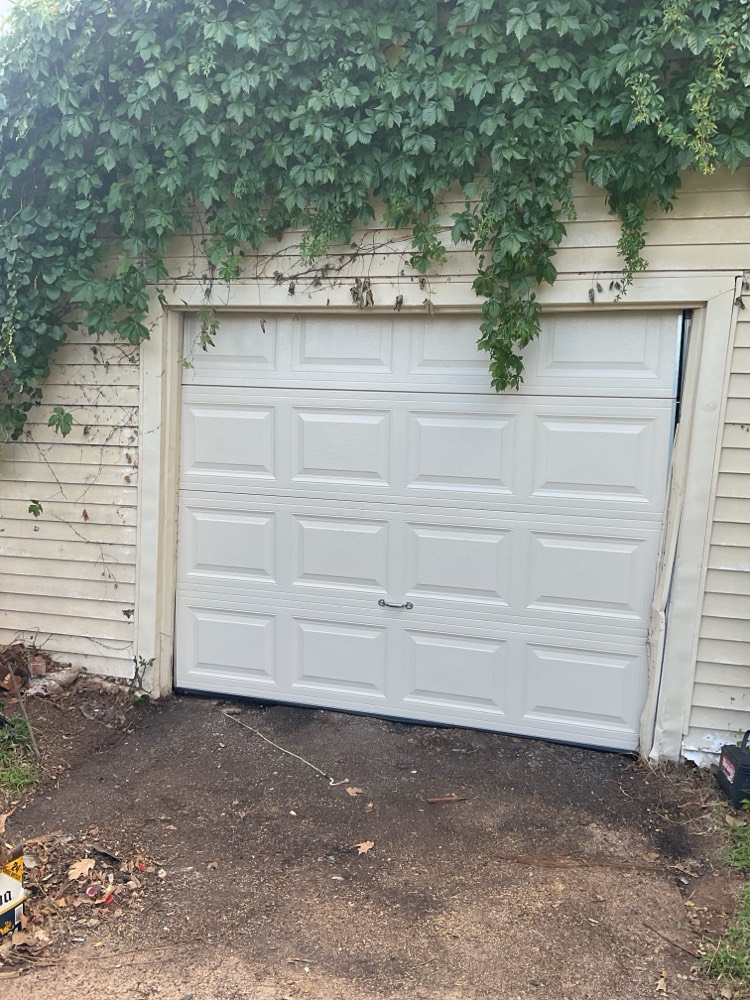 Newly installed white garage door with raised panel design on residential home.