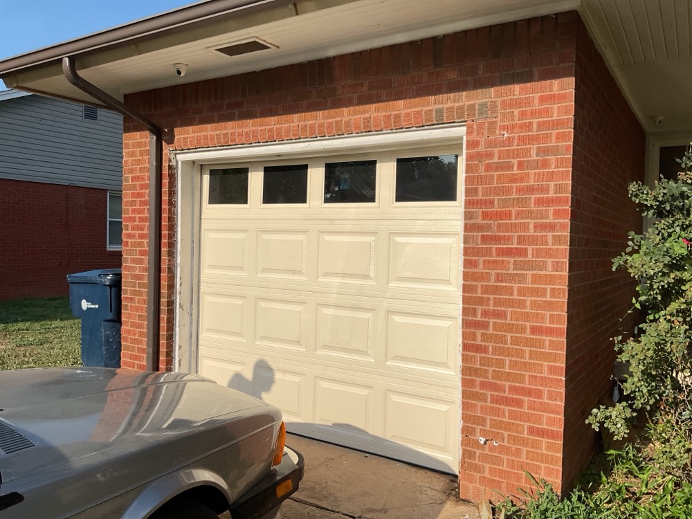Cream garage door with four windows installed on brick home exterior