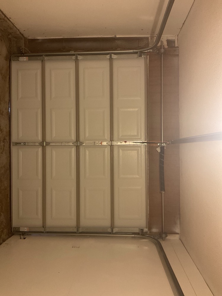Interior garage door installation with white panels and metal framing