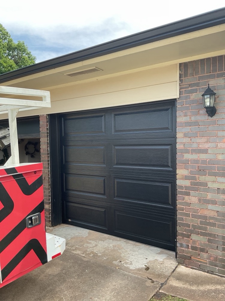 Finished black garage door installation on residential home