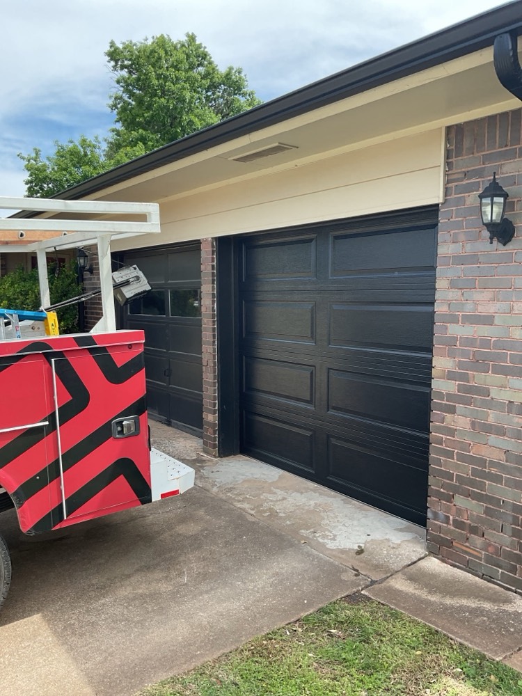 Completed black garage door installation on brick home in Oklahoma City