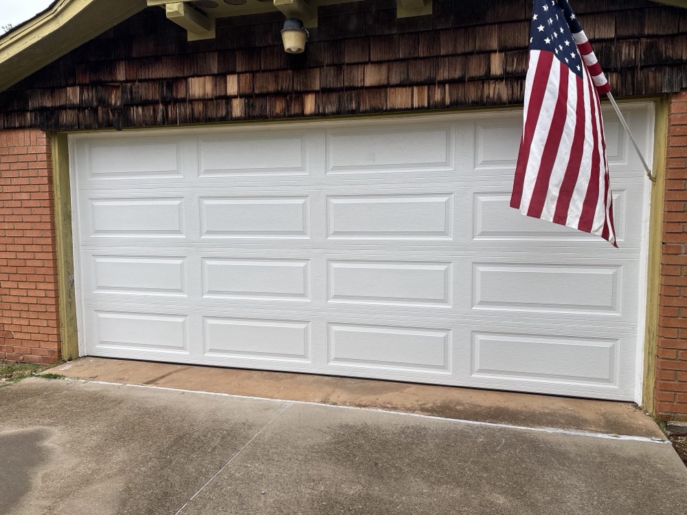 Newly installed white garage door on brick home