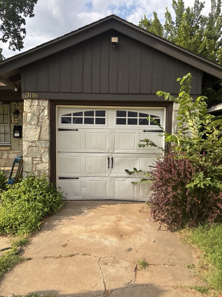 Newly installed white garage door with recessed panels and hardware on Oklahoma City residence
