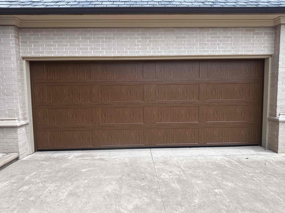 Newly installed wood-finish garage door on residential driveway