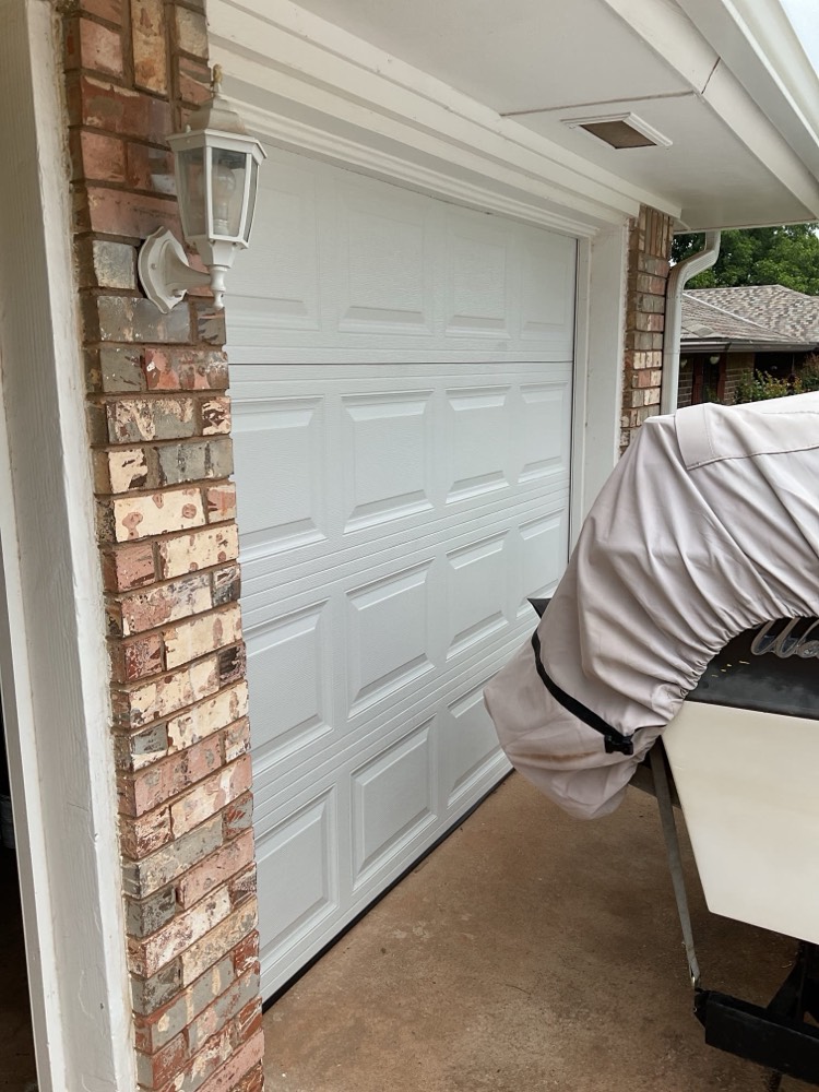 White residential garage door with brick trim installed in garage