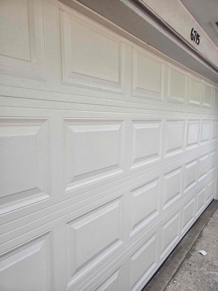 Newly installed white garage door with raised panel design