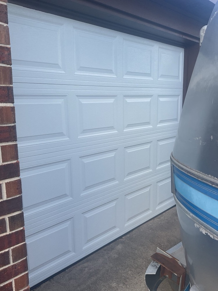 White raised-panel garage door installed on brick home exterior