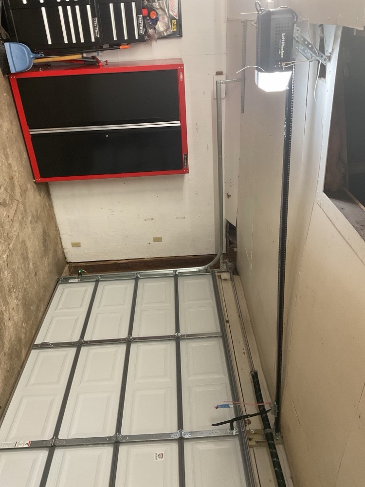 Completed garage door installation with white sectional panels and mounted opener in Oklahoma City