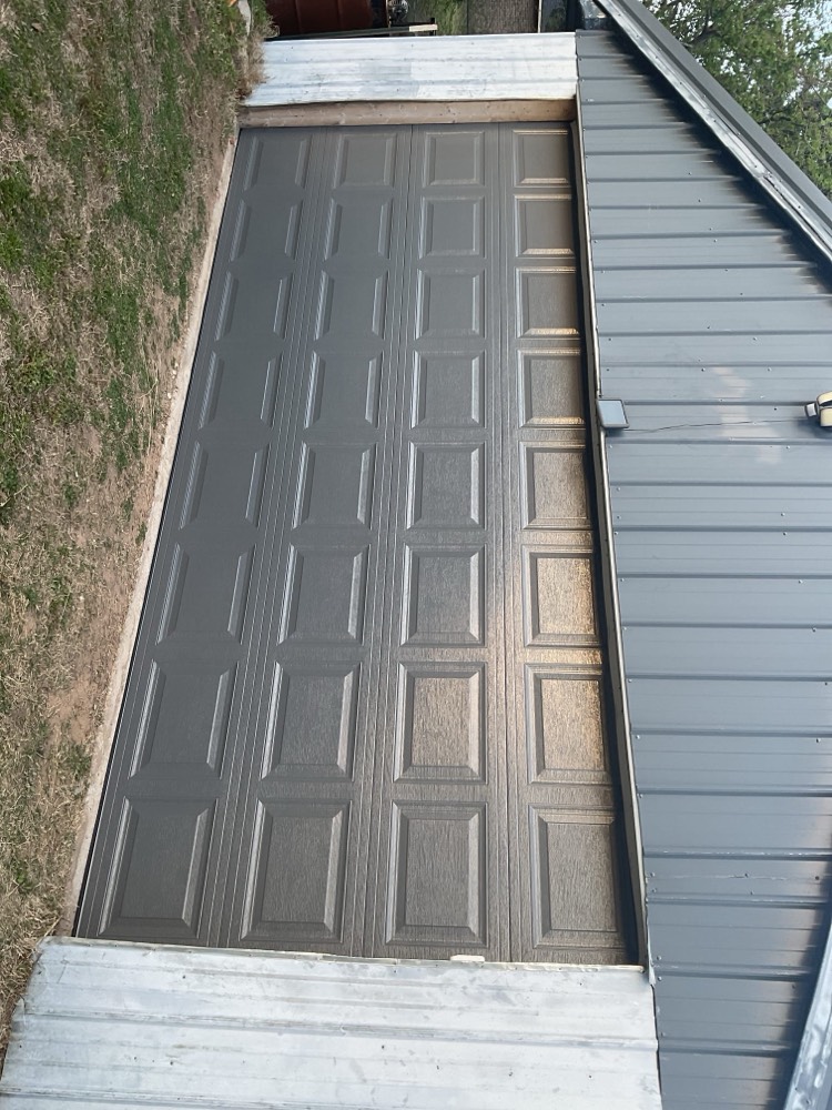 Newly installed gray garage door with geometric panel pattern on residential driveway in Oklahoma City
