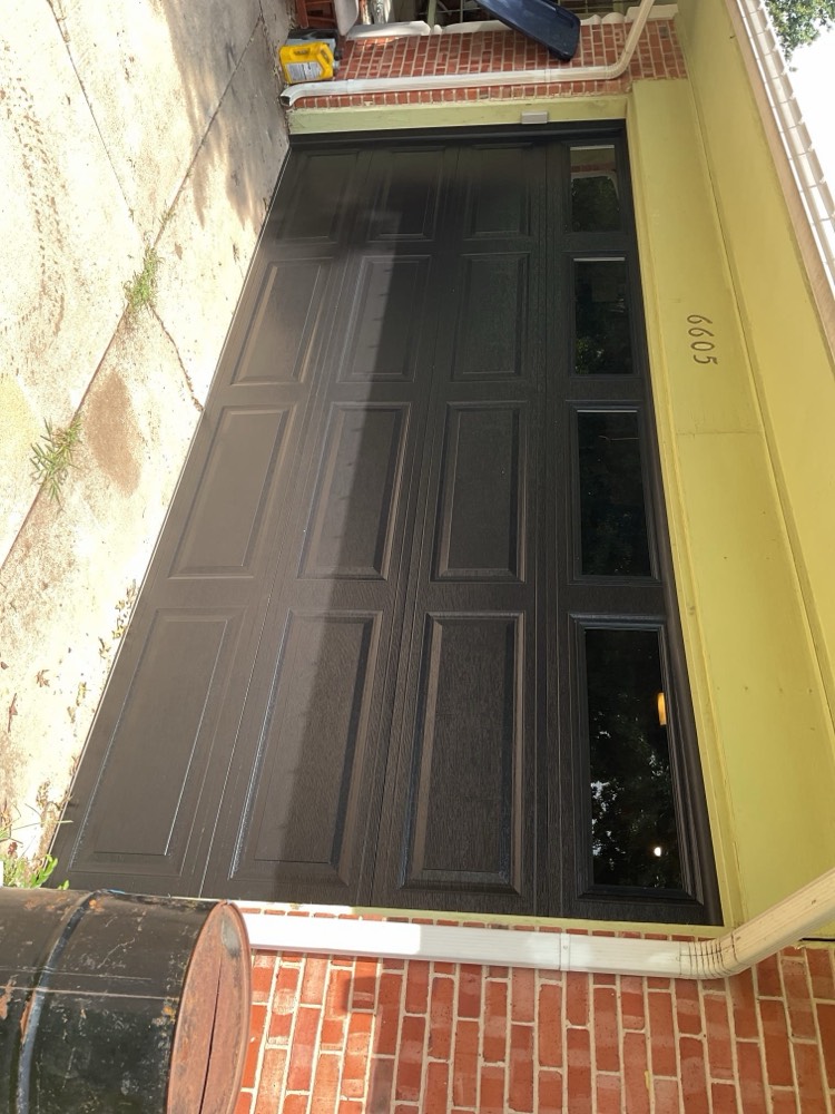 Black paneled garage door installed on residential home