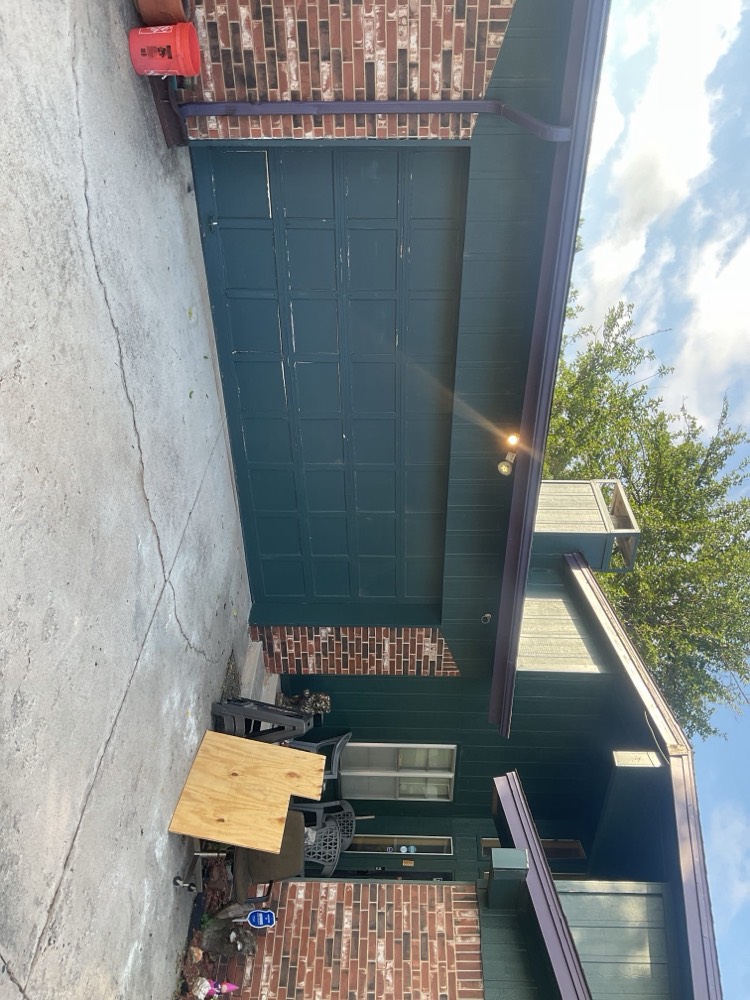 Dark green garage door installed on brick home.