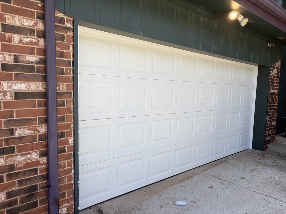 Newly installed white garage door on brick garage.