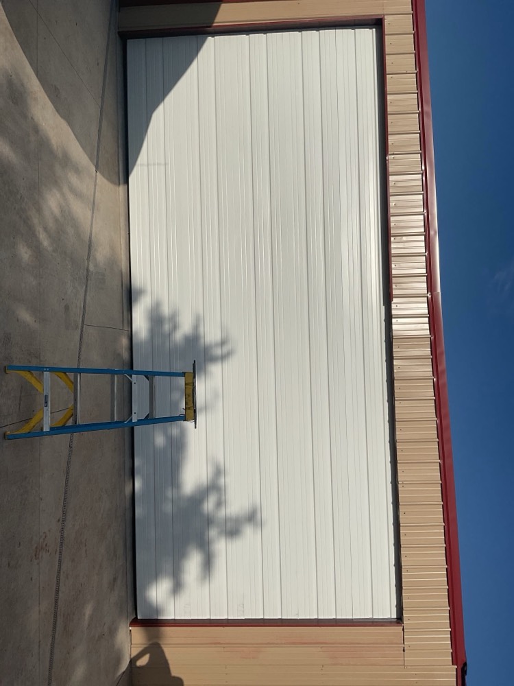 Newly installed white garage door with dark frame on residential building in Prague, OK