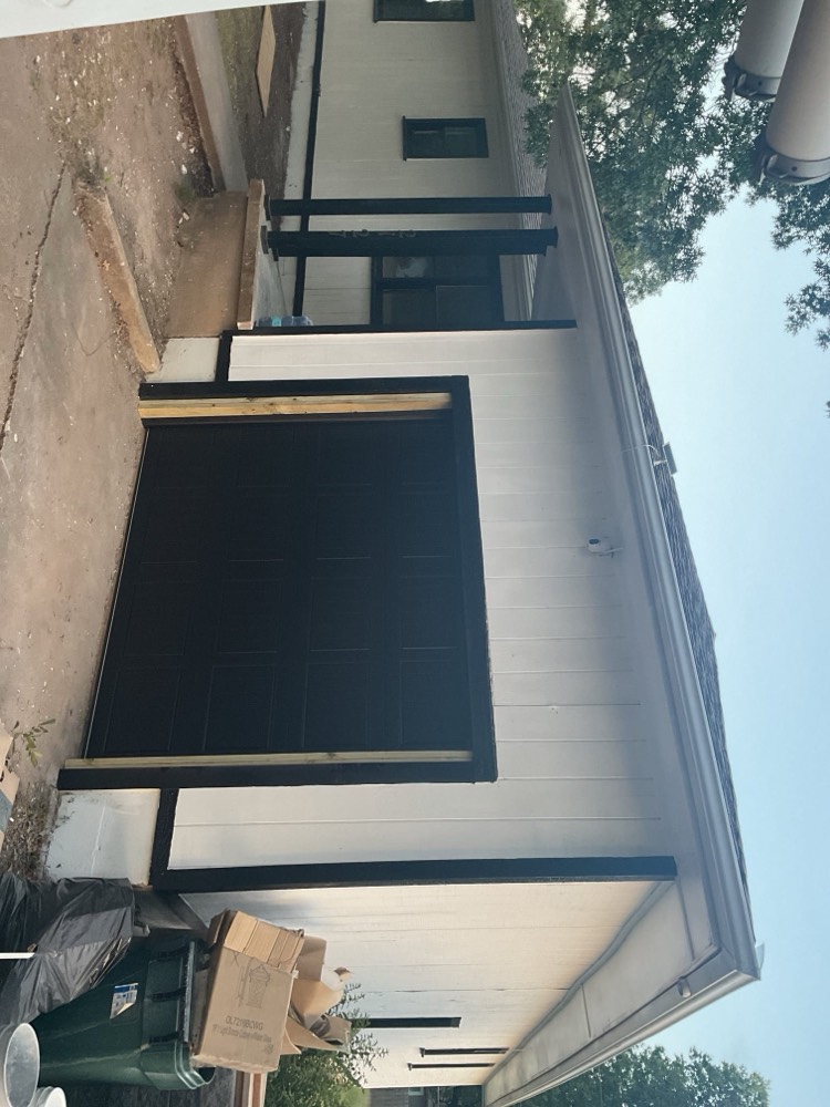 Installed black garage door with decorative hardware on home