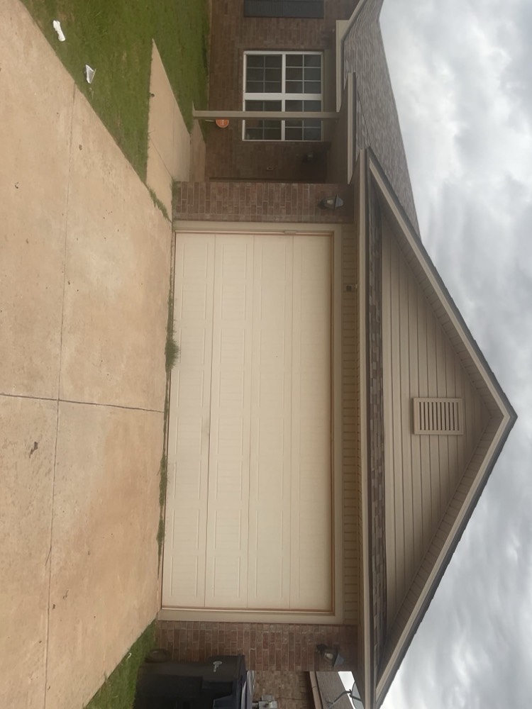 Finished white garage door installation on brick and siding home exterior