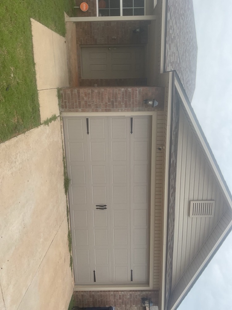 Newly installed white garage door with panel details on residential home