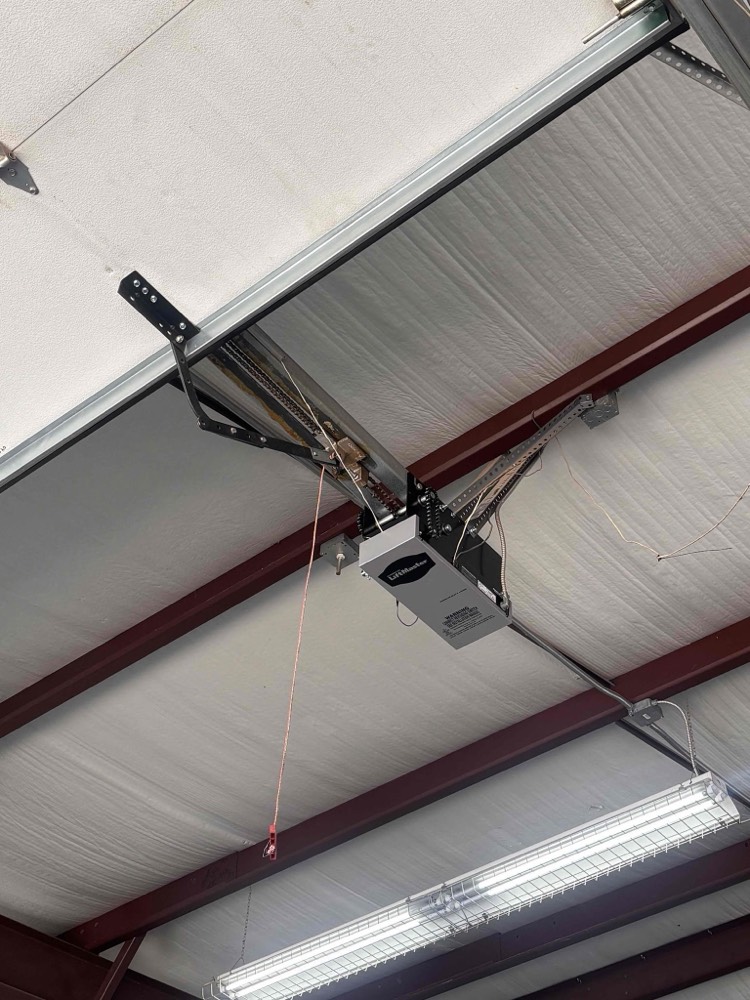 Installed garage door opener mounted to ceiling with red structural beam and wiring