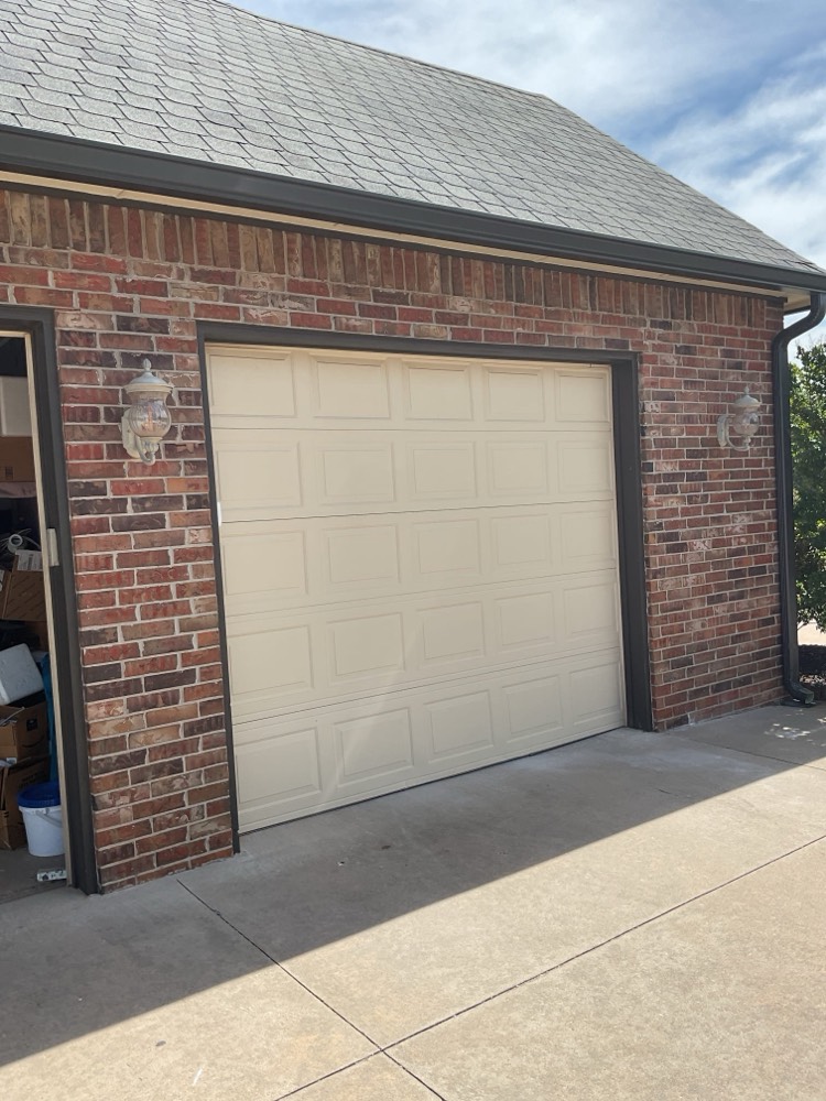 Installed cream-colored garage door on brick residential garage