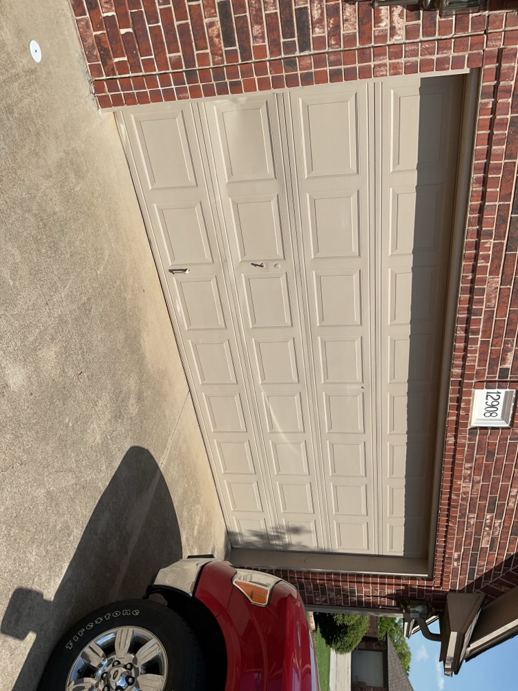 Two-panel beige garage door installed on residential brick home