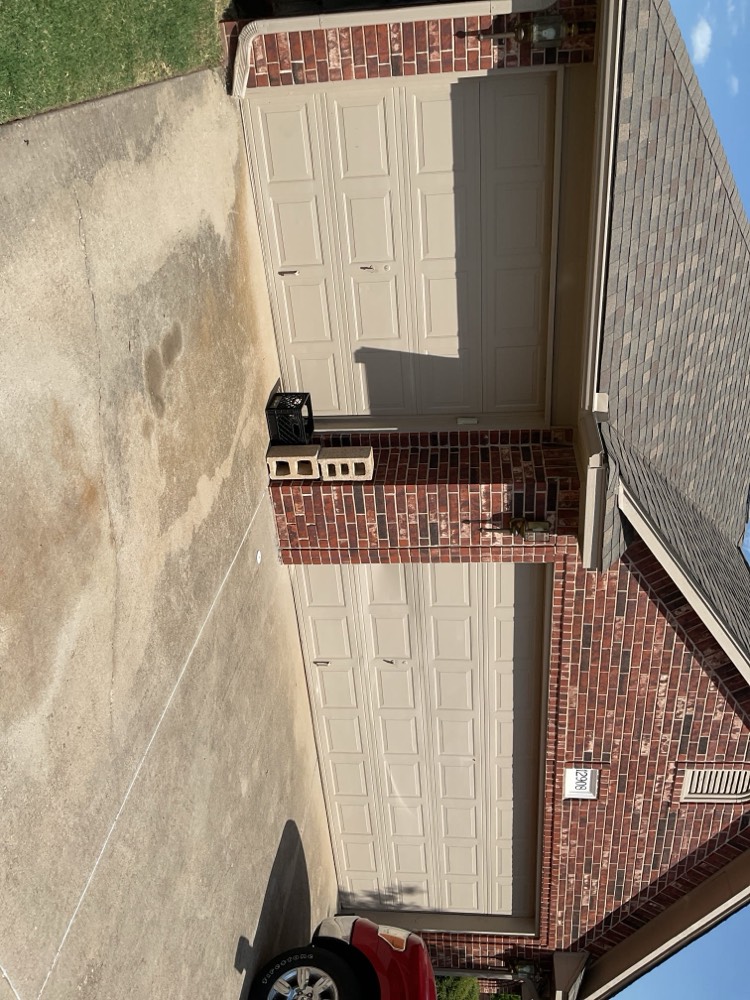 Newly installed two-panel beige garage door on brick home exterior