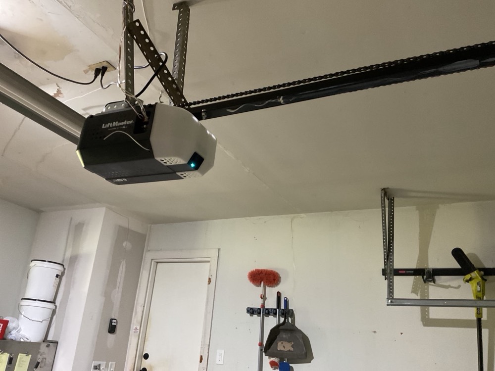 Installed garage door opener motor and rail assembly mounted to ceiling