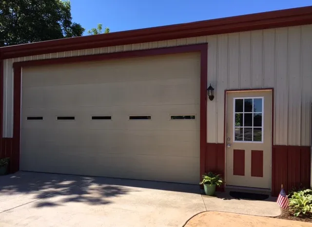 Flush panel garage door with windows installed on outbuilding in Oklahoma City area by Affordable Door Co