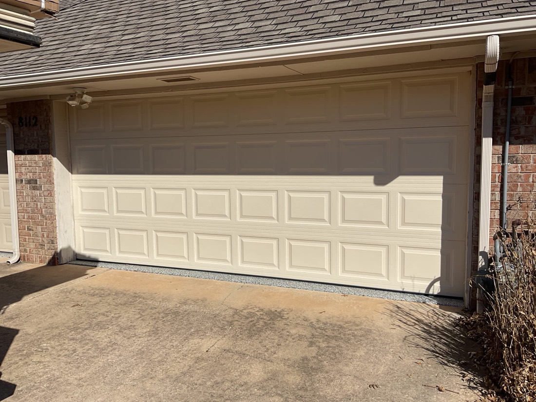 Cream-colored garage door with multi-panel design on residential home