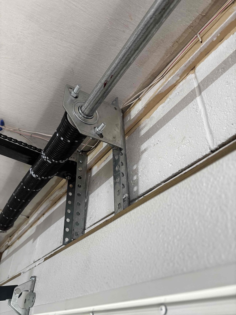 Torsion spring and pulley bracket mounted on garage door frame