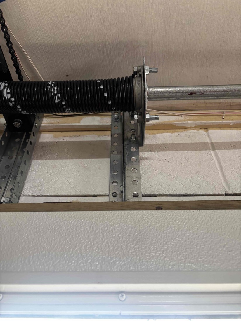 Torsion spring and mounting hardware on garage door frame