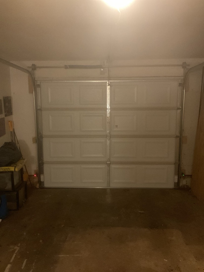 Newly installed white two-car garage door with overhead hardware in residential garage