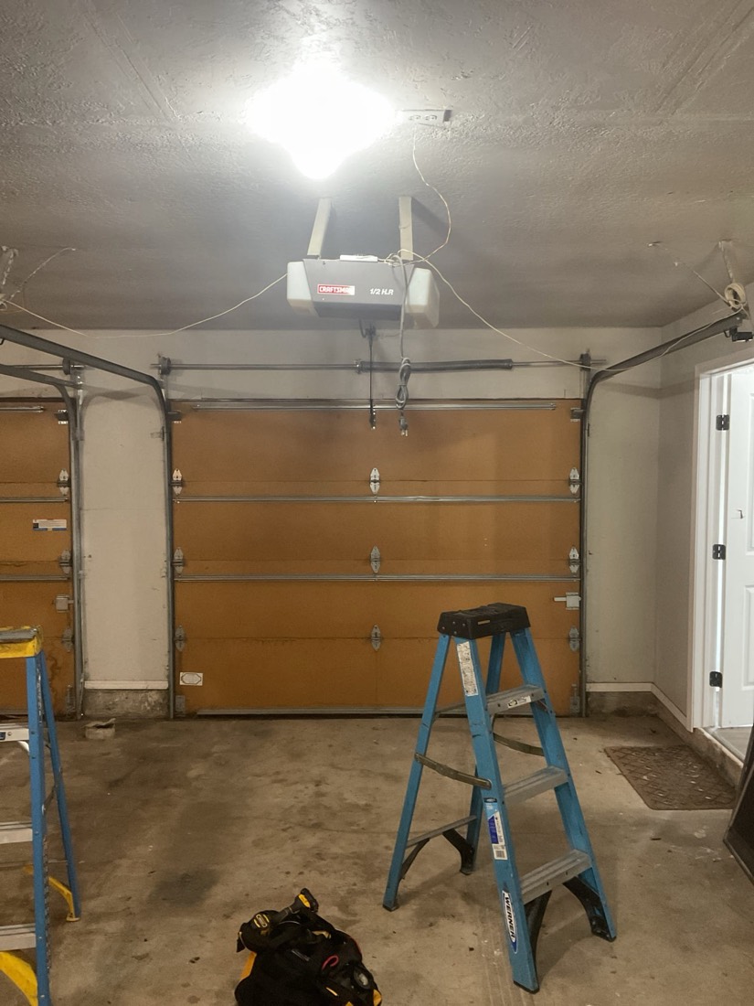 Garage interior with newly installed wood-tone door panels and opener system.