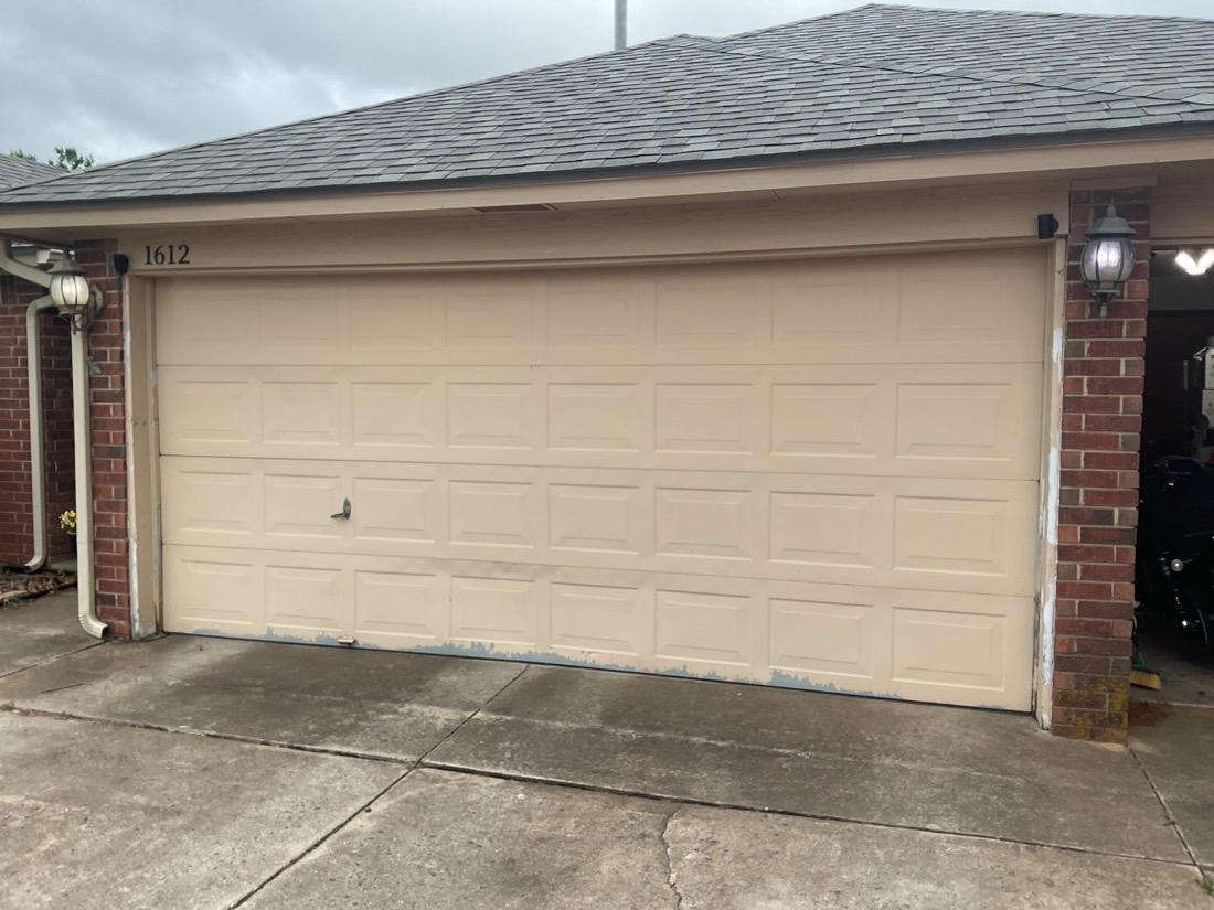 Newly installed cream garage door with clean appearance on brick exterior