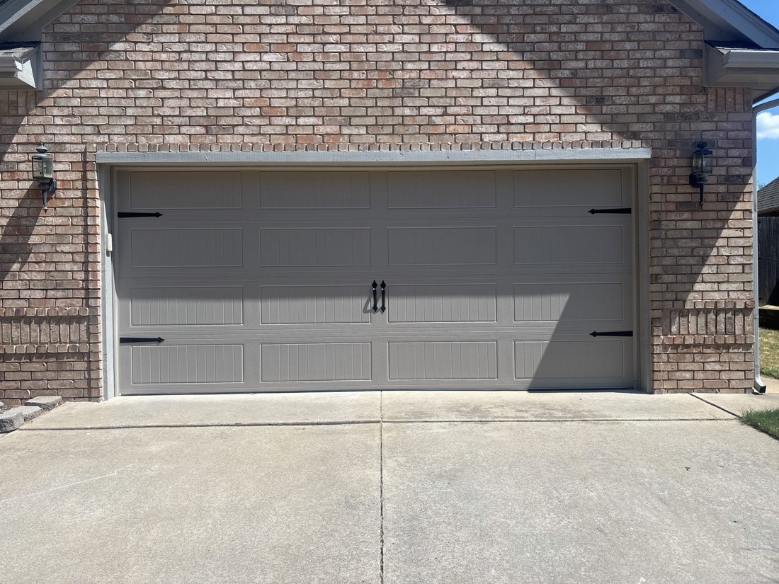 New gray residential garage door on brick home with concrete driveway in Edmond, OK