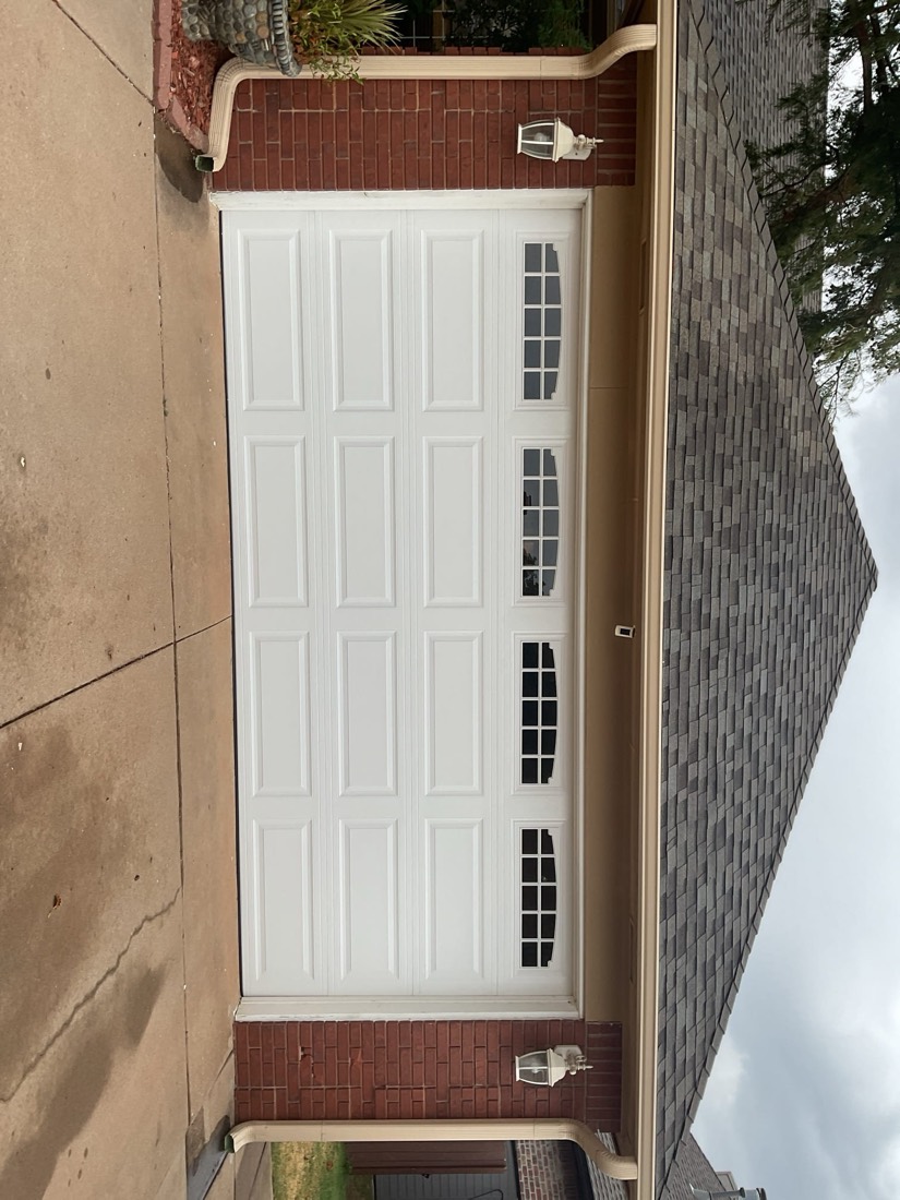 White paneled garage door with windows on brick home