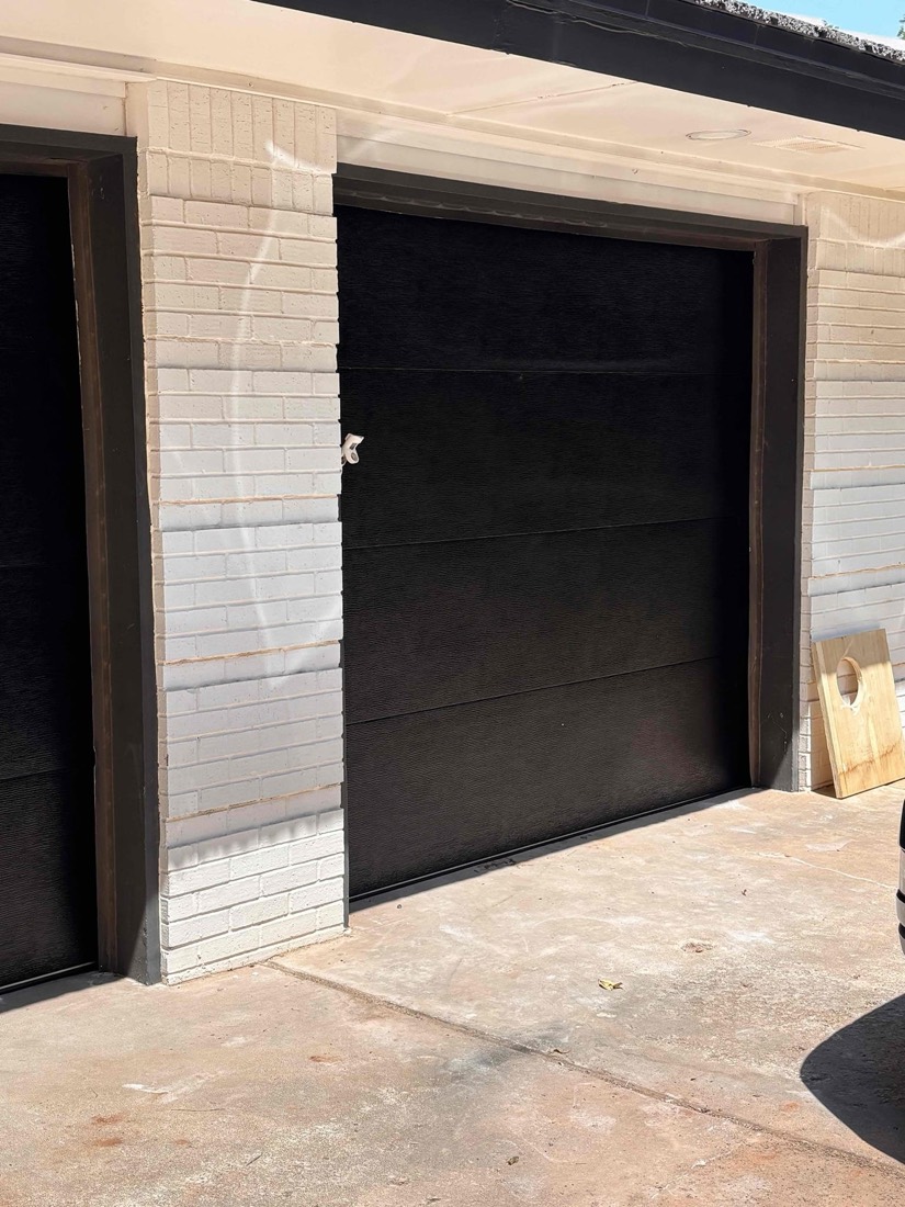 Black garage door with white brick surround and dark frame in Edmond