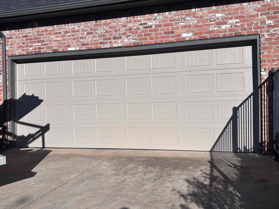 White paneled garage door installed on brick home exterior