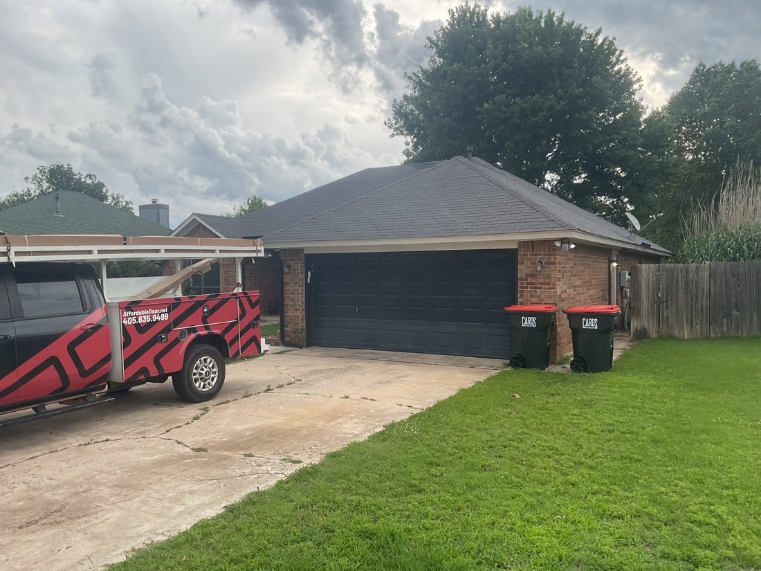 Completed black garage door installation on residential property