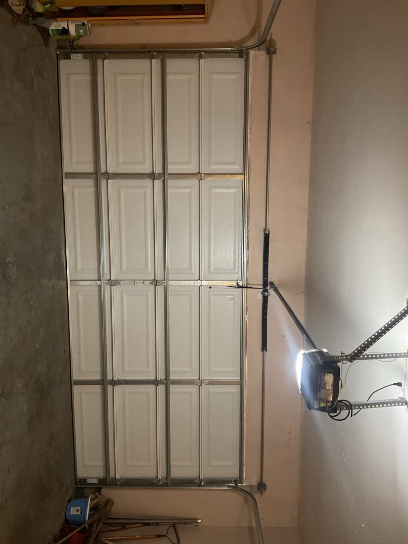 Installed white garage door with segmented panels and metal frame