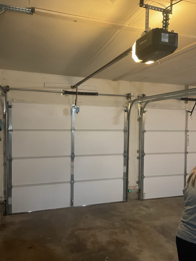Three white residential garage doors with installed openers and hardware.